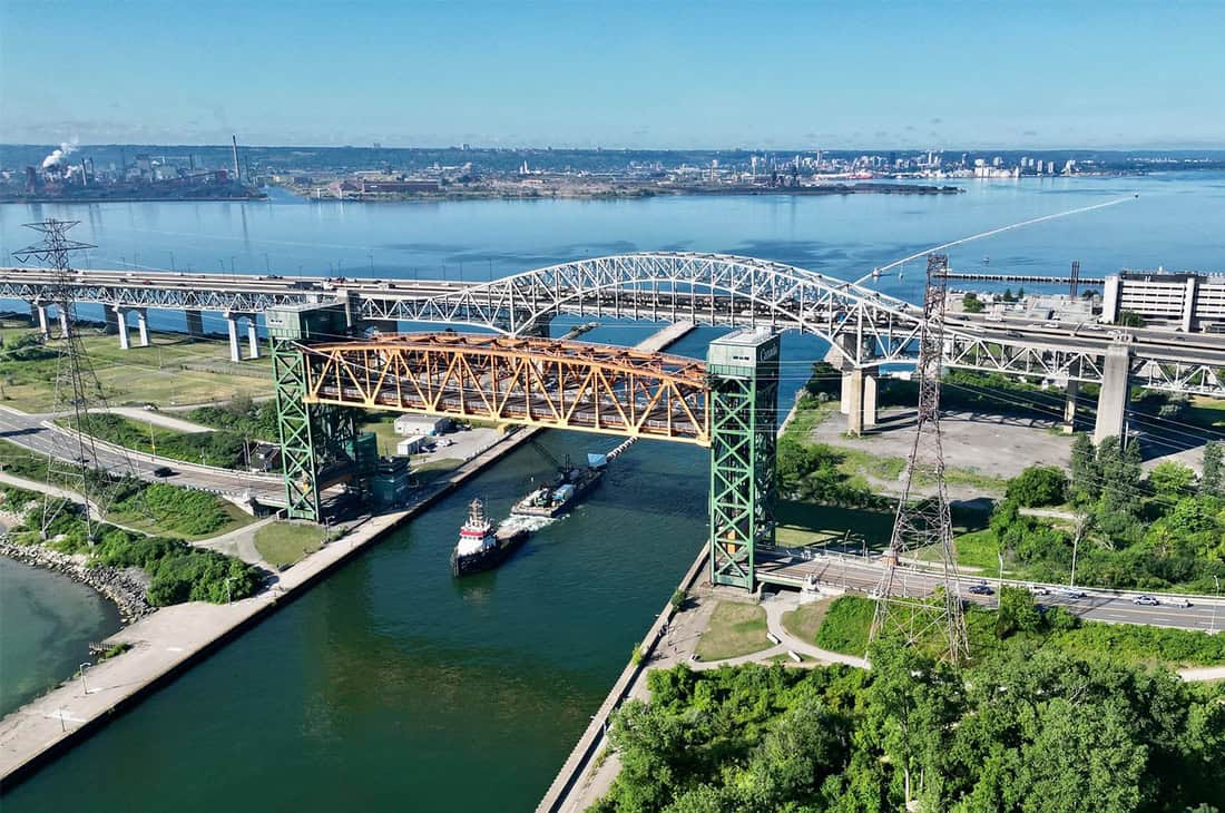 Picton Terminals’ Amy Lynn D tug under bridge w huge pipe. Photo provided by Picton Terminals.